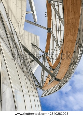 A low-angle view of the Louis Vuitton Foundation's stunning glass facade and wooden structure, showcasing its contemporary design against the Parisian sky.