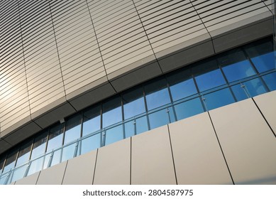 A low-angle view of a modern building facade featuring glass panels and metal cladding, with clean linear architectural details.