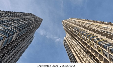 Low-angle view of modern high-rise buildings under a clear blue sky, showcasing urban architecture, symmetry, and cityscape design - Powered by Shutterstock