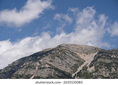 The low-angle view of a mountain under the blue sky with clouds