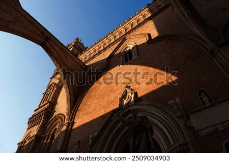 Low-angle view of Palermo Cathedral's Gothic architecture, stone details and dramatic shadows cast by the afternoon sun, historic Sicilian landmark