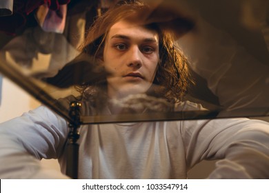 Low-angle view portrait of an addicted teenage boy staring while experiencing psychotropic effects caused by snorting cocaine 