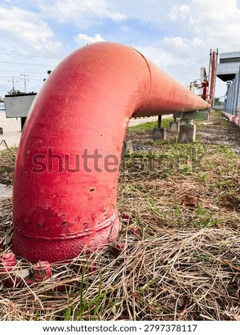 Low-angle view of a red fire water pipeline installed in an industrial facility. Fire protection infrastructure and emergency safety system designed for industrial plants, fuel terminals and oil and gas operations.