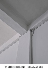 Low-angle view of a reinforced concrete column and beam inside a building with visible electrical conduit installation. The architectural perspective highlights structural geometry, making it suitable for construction, engineering, architecture, building inspection, and infrastructure concepts.
