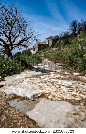 Low-angle view of a stone path leading to the medieval Agii Asomati chapel on Penteli Mountain near Athens, Greece, built beside a spring and old marble quarries.