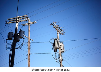 Low-angle View Of Three Old Utility Poles With Cables And Transformers For Telecommunication And Electricity Against Clear Blue Sky With Copy Space