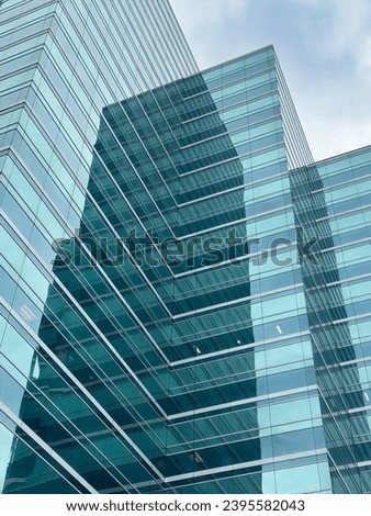 Low-angle view of two office buildings of steel and glass near each other, one with distorted reflections, under an overcast sky in downtown Jacksonville, Florida, for urban and architectural motifs