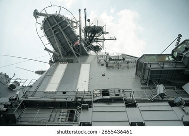Low-angle view of the USS Intrepid's command tower featuring satellite dishes, antennas, and viewing platforms. The steel structure reflects the carrier s role in naval communication and observation.