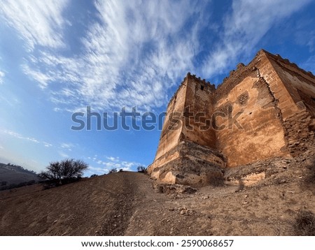 A low-angle view of the wall and a tower of the Boulaouane Kasbah.