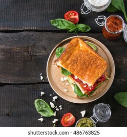 Low-carb Gluten Free Cloud Bread Veggie Sandwich With Spinach, Avocado, Feta Cheese, Tomatoes And Pesto Sauce, Served On Plate With Jars Of Ingredients Over Wood Background. Top View, Square Image