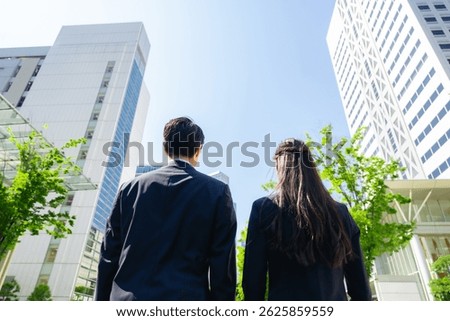 lower angle shot of the backs of a group of business people standing in a city with fresh greenery