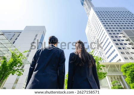 lower angle shot of the backs of a group of business people standing in a city with fresh greenery