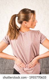 Lower Back Pain; Blonde European Woman With Pigtail From Behind Holding Hands On Her Back