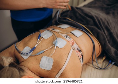 Lower Back Physical Therapy with TENS Electrode Pads, Transcutaneous Electrical Nerve Stimulation. Electrodes onto Patient's Lower Back. High quality photo
