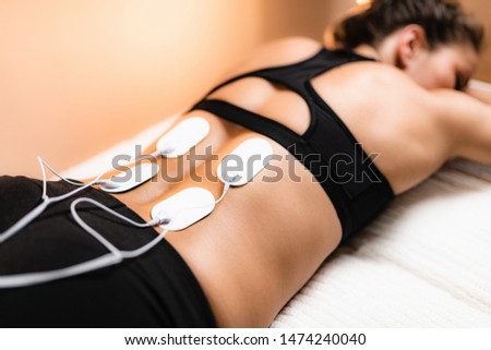 Lower Back Physical Therapy with TENS Electrode Pads, Transcutaneous Electrical Nerve Stimulation. Electrodes onto Patient's Lower Back