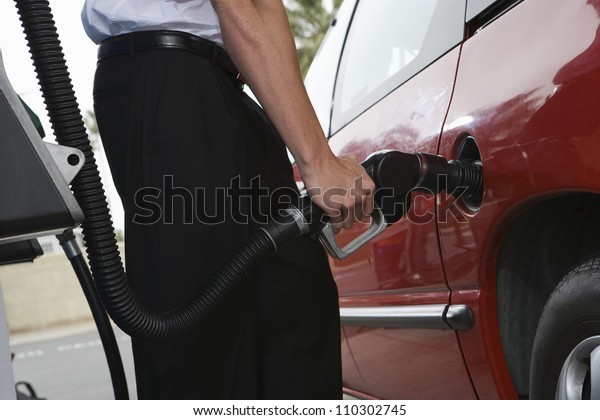 Lower body of a man\
refueling a car