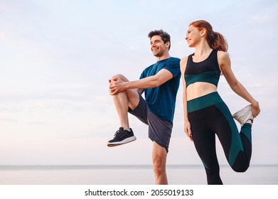 Lower couple young two friend strong sporty sportswoman sportsman woman man in sport clothes warm up training do stretch exercise on sand sea ocean beach outdoor jog on seaside in summer day morning
