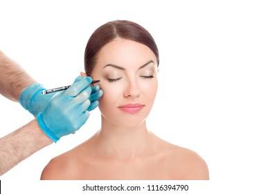 Lower eyelid reduction wrinkles removal plastic surgery cosmetic operation concept Woman eyes closed, doctor surgeon hand in gloves  on patient face drawing cut line isolated white background.