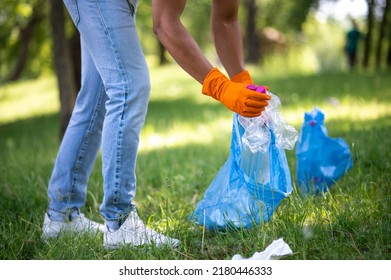 Lower half of man picking up trash in park - Shutterstock ID 2180446333