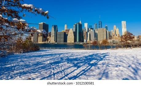 Lower Manhattan Skyline Panorama In Snowy Winter Time From Brooklyn Bridge Park Riverbank, New York City, USA