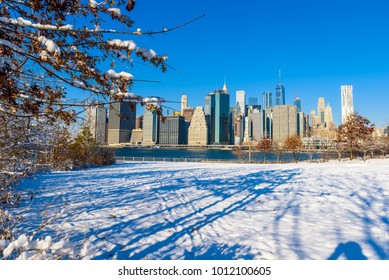 Lower Manhattan Skyline Panorama In Snowy Winter Time From Brooklyn Bridge Park Riverbank, New York City, USA