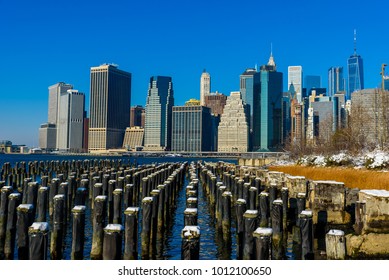 Lower Manhattan Skyline Panorama In Snowy Winter Time From Brooklyn Bridge Park Riverbank, New York City, USA