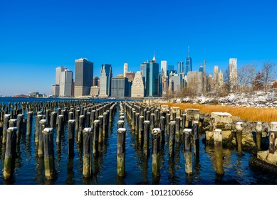 Lower Manhattan Skyline Panorama In Snowy Winter Time From Brooklyn Bridge Park Riverbank, New York City, USA