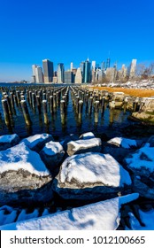 Lower Manhattan Skyline Panorama In Snowy Winter Time From Brooklyn Bridge Park Riverbank, New York City, USA