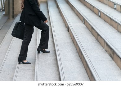 Lower part of business woman in formal suit walking up the outdoor stair.