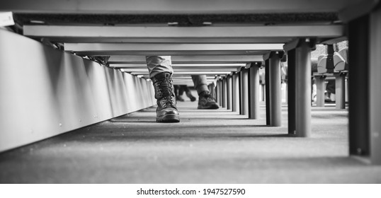 Lower part of the leg with the boot of a seated man. View under the train seats. Black and white photography