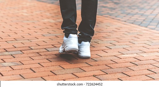 lower part of the male legs in white sneakers on the road made of bricks - Shutterstock ID 722624452