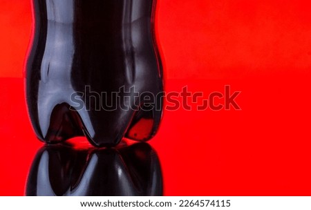Lower part of a plastic bottle of Coca cola on a red background