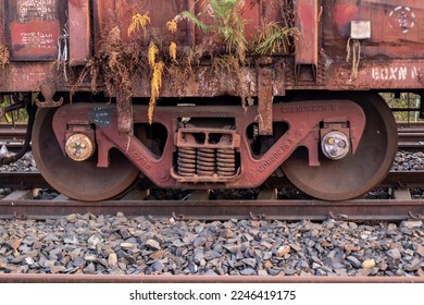 The lower portion of an old, rusty railway carriage that included the chassis (side frame, spring plank, springs, suspension with wheels), standing on rails.