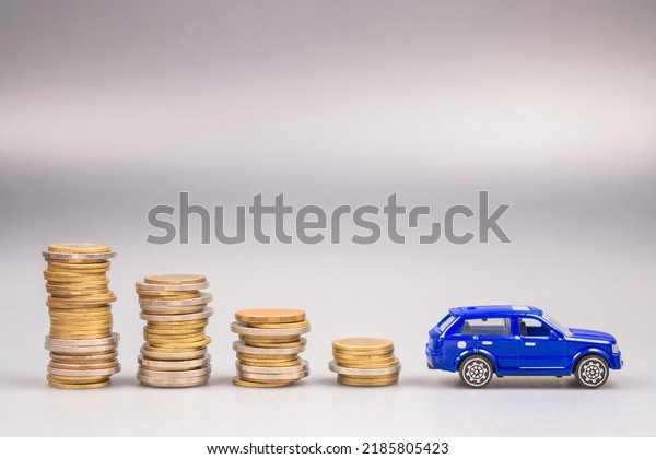Lower stack money with a small blue\
car at the end, save the money for buying a new car, car and\
budget, finance and insurance, use money less about the\
car
