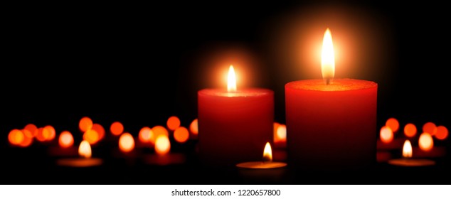 Low-key studio shot of elegant advent candles with two flames in the foreground, black background with defocused flames - Powered by Shutterstock