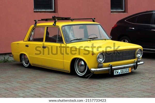 Lowrider in body of an\
old Soviet car VAZ 2101 Kopeika, Zhiguli at Old Car. Yellow retro\
car VAZ 2101 parked. ВАЗ Жигули 2101. Lowering racing air\
suspension in the city\
street.