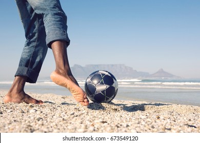 Lowsection of a man playing soccer on beach