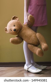 Lowsection Side View Of A Girl Holding Teddy Bear In Home