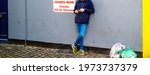 Low-section of young man reading using smartphone telephone next to Private Road Vehicles will be removed signage waste bags