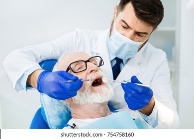 Loyal Client. Close Up Of Skilled Stomatologist Using Dental Equipment While The Patient Sitting On The Chair With A Mouth Open