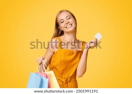 Loyalty Program Concept. Happy Young Woman Holding Shopping Bags And Credit Card Over Yellow Background, Received Bonus After Purchase