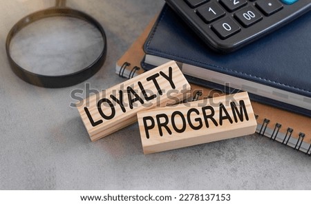 Loyalty program text on wooden blocks and on gray table with magnifier and calculator.