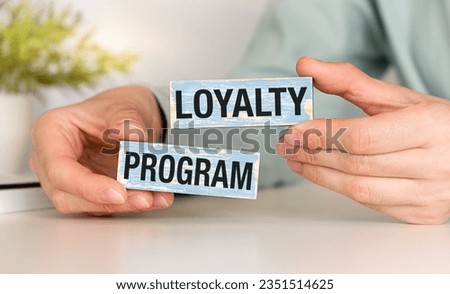 Loyalty program text on wooden blocks and on gray table with hands.