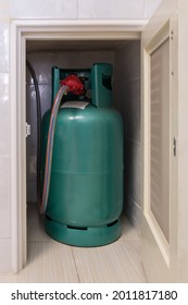 The LPG Gas Tank For Cooking Is Stored In The Small Storage Compartment Near The Gas Stove Bar In The Kitchen, Front View For The Copy Space.