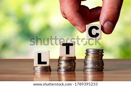 LTC word symbol - business concept. Hands put wooden block on stacked increasing coin.