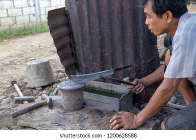 LUANG PRABANG, LAOS - OCTOBER 8: An Unidentified Man Checks For Warps In A Knife At A Local Village Forge In Luang Prabang, Laos On October 8, 2017.