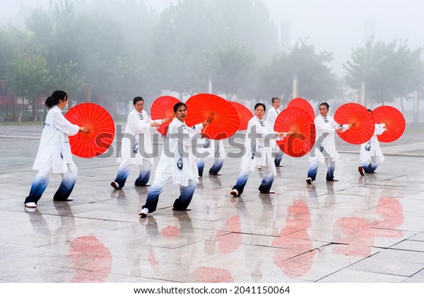 Luannan County, Tangshan city, Hebei Province,\
China: September 11, 2021: Women practice Chinese Tai Chi fan dance\
at Wutian Square