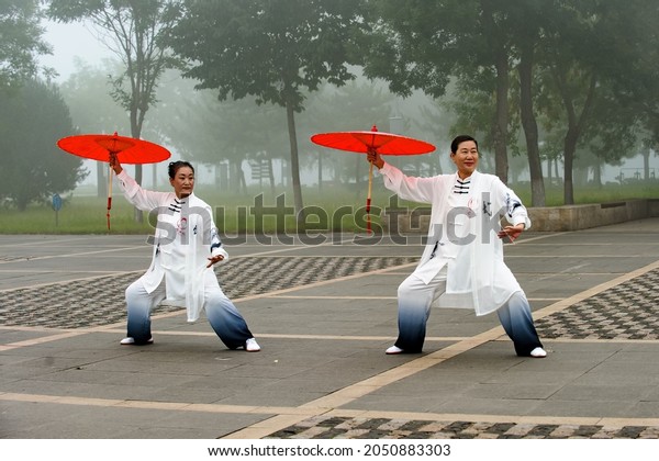 Luannan County, Tangshan city, Hebei Province,\
China: September 11, 2021: Women practice Chinese Tai Chi fan dance\
at Wutian Square