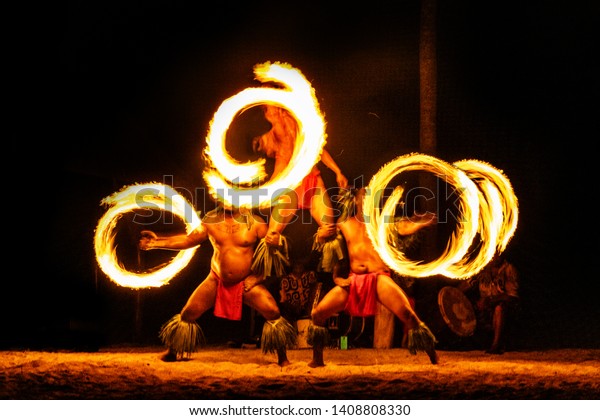 Luau hawaiian fire dancers motion blur tourist\
attraction in Hawaii or French Polynesia, traditional polynesian\
dance with men dancer.