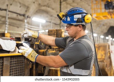 LUBIN, POLAND - OCTOBER 7, 2019 : Blue Color Worker Repairs Loading Machine In Copper Mine That Belongs To KGHM Polska Miedz.